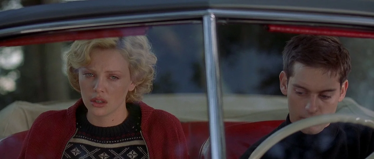 The Cider House Rules movie still: medium — A man and woman sit side by side in the front of a red convertible. Both figures appear focused forward…