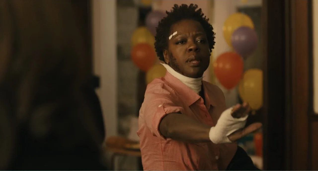 Lila & Eve (2015) movie still: medium — A dimly lit room with several colored party balloons visible in the background. A woman in a pink shirt…