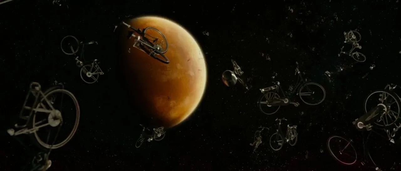 Mr. Nobody (2009) movie still: wide — A vast expanse of deep space features a large, glowing orange planet on the left. Numerous bicycles float in…