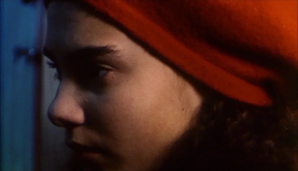 Nenette et Boni (1996) movie still: closeup — A close-up view of a woman wearing a bright orange beret in a room. The subject's face is partially…