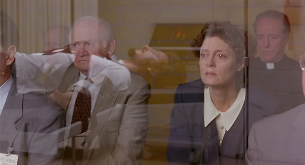 Dead Man Walking (1995) movie still: medium — A group of people watch from behind a glass window in a sterile room. Susan Sarandon sits in the…