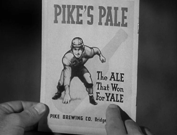 The Lady Eve (1941) movie still: closeup — A close view shows two hands holding a vintage print advertisement for an ale. The graphic displays a…