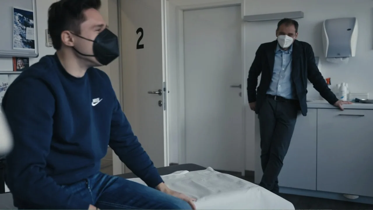 Federico Chiesa - Back on Track (2023) movie still: medium — A clean medical examination room contains a patient table and diagnostic furniture. A…