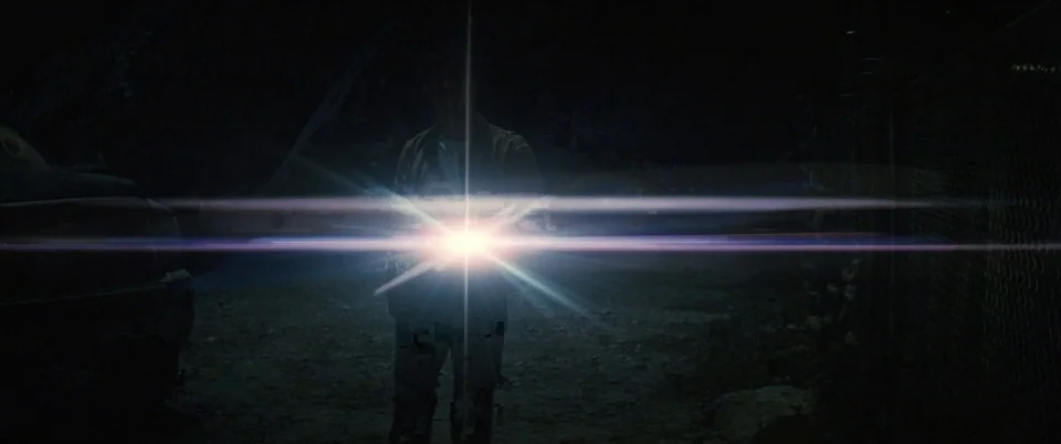 Interstellar (2014) movie still: fullbody — A dark, unpaved outdoor area features a fence and the silhouette of a vehicle. A person stands facing…