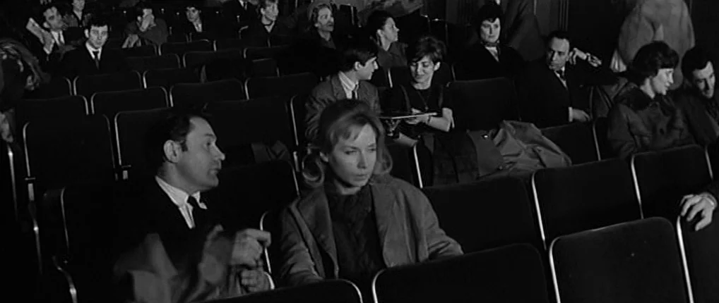 Antoine and Colette (1962) movie still: medium — A rows of seats in a darkened auditorium filled with an audience. A man and a woman occupy adjacent…