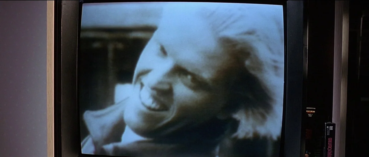 The Frighteners (1996) movie still: closeup — A close-up view of a television screen showing a person's face. The screen image is captured from an…