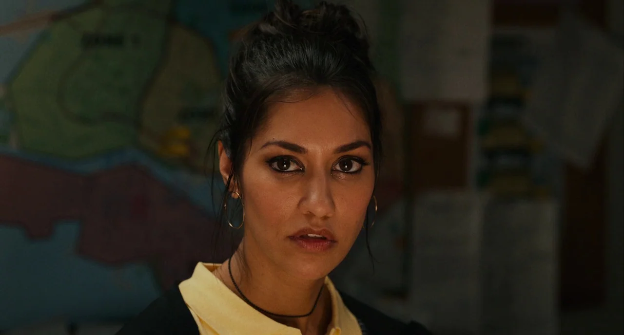 Blindspotting (2018) movie still: closeup — An indoor workspace contains a map visible on the blurred wall behind the subject. A woman with dark…