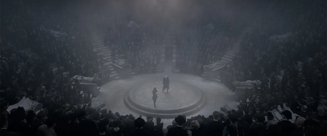 Fantastic Beasts: The Crimes of Grindelwald (2018) movie still: wide — A stone circular amphitheater is packed with a large silent crowd under heavy…