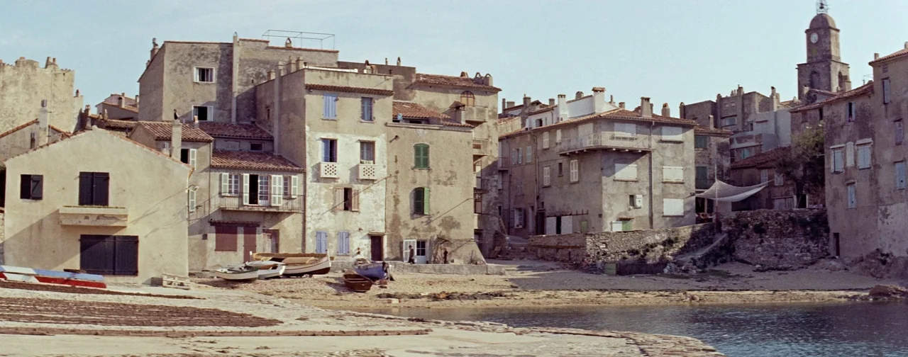 And God Created Woman (1956) movie still: establishing — A quiet Mediterranean coastal village features multi-story stone buildings with shuttered…
