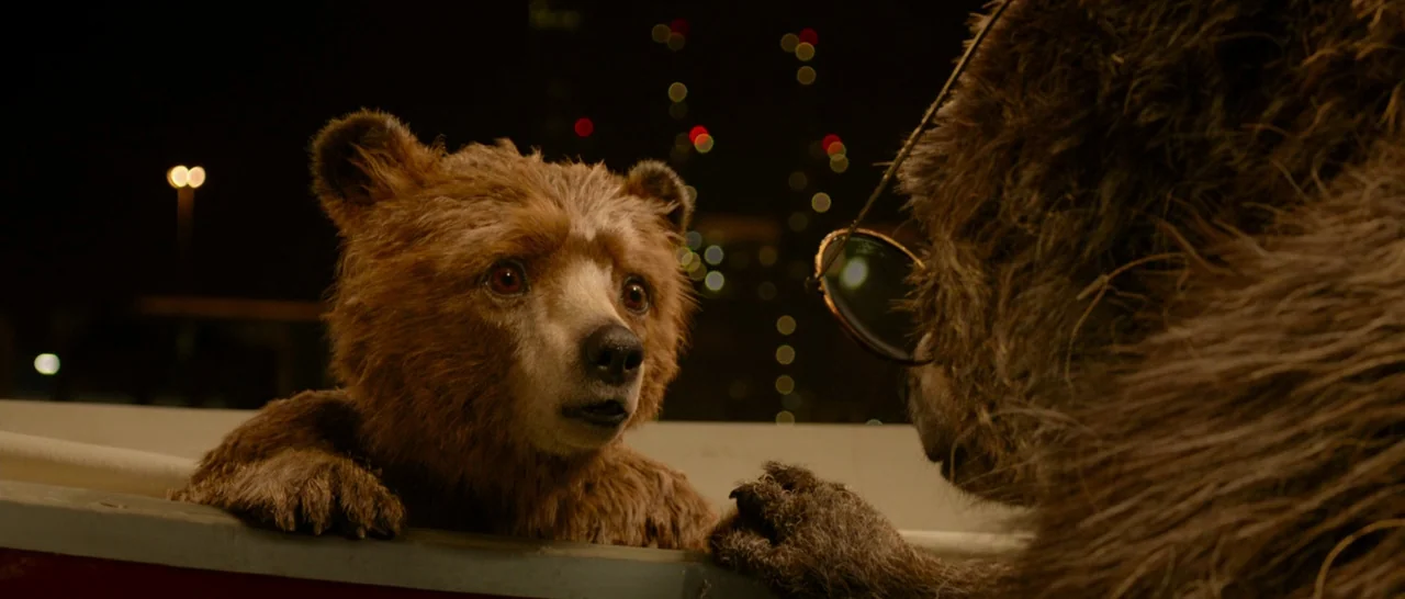 Paddington (2014) movie still: medium — Two bears stand near a railing on a boat deck during the night. The younger bear faces the older bear who…