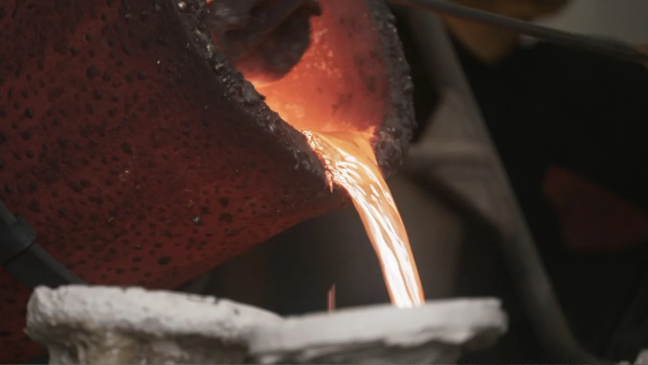Victoria's Secret: The Tour '23 (2023) movie still: closeup — A heavy dark crucible tips to release a stream of bright glowing molten metal. The…