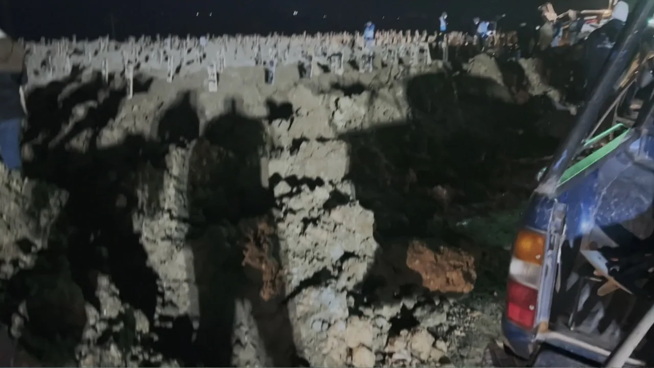 Death Without Mercy (2024) movie still: wide — A night view of a dirt-filled burial site with numerous headstones in the background. People stand…