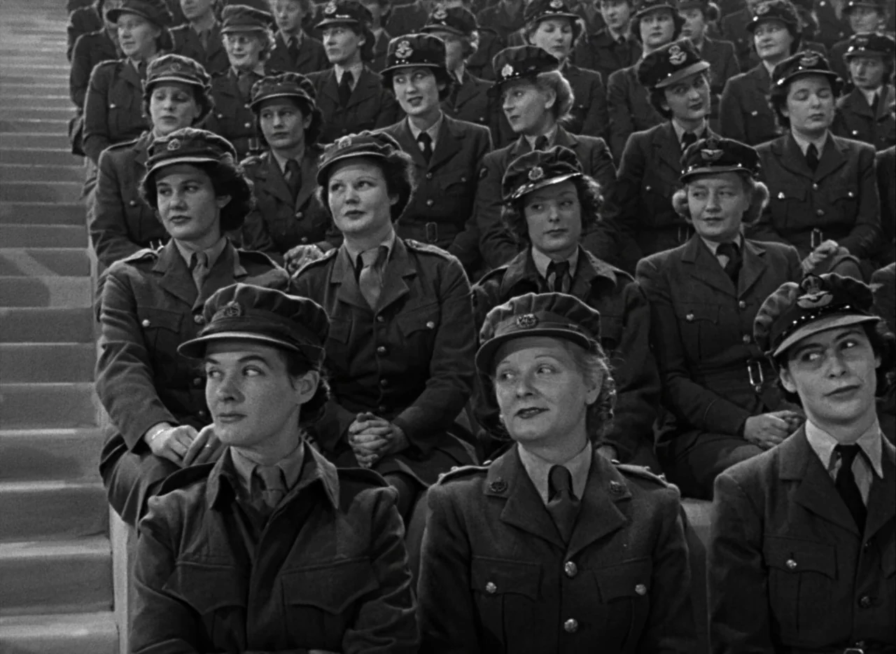 A Matter of Life and Death (1946) movie still: medium — A large crowd of women in 1940s military uniforms sit in tiered rows. They sit in neat…