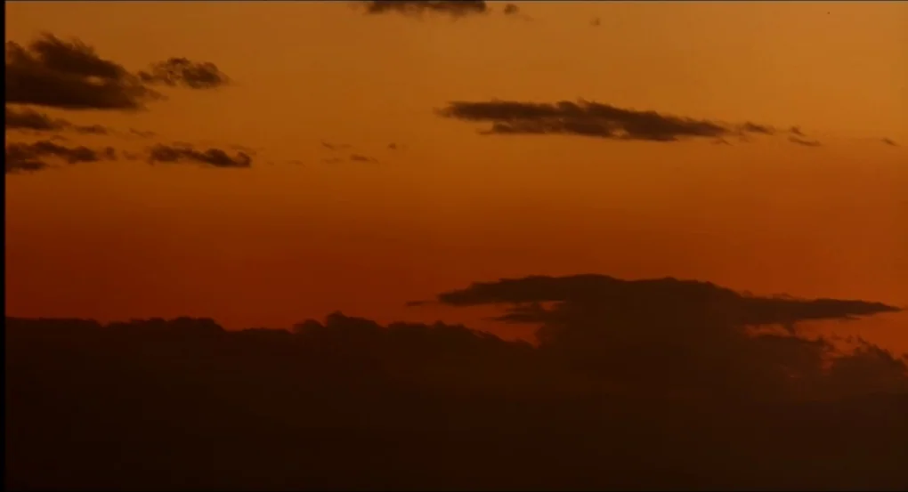 My Own Private Idaho (1991) movie still: establishing — A vast sky is filled with layered clouds during the late golden hour. The clouds appear as…