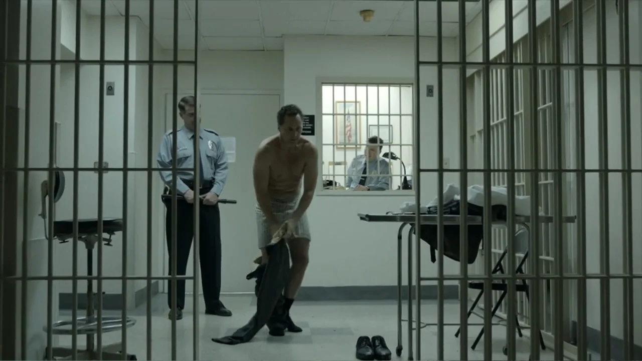 All the Way (2016) movie still: fullbody — A sterile holding cell features pale green walls, tiled flooring, and iron bars.
