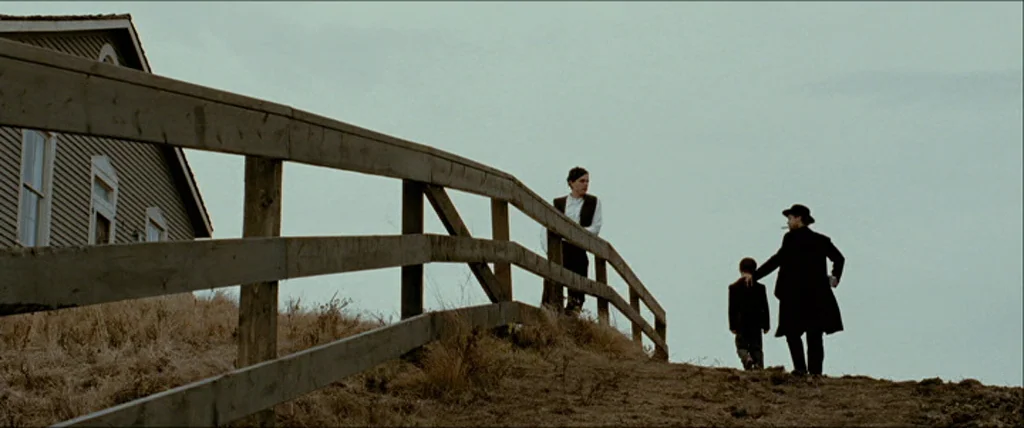The Assassination Of Jesse James By The Coward Robert Ford (2007) movie still: wide — A wooden rail fence runs along a dry, grassy slope beneath an…