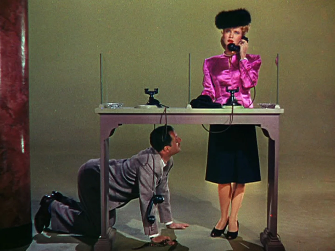 Ziegfeld Follies (1945) movie still: fullbody — A stylized minimalist studio setting features a lone table against a plain wall. A woman speaks into…