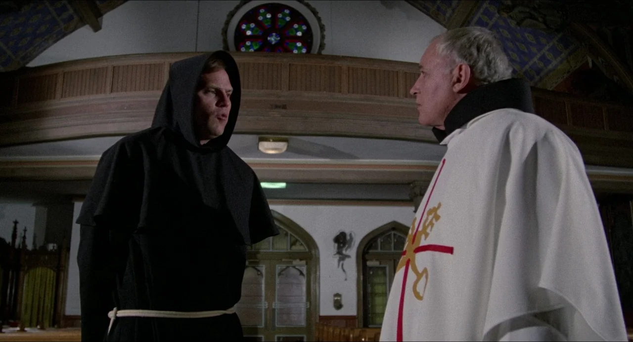 The Amityville Horror (1979) movie still: medium — The interior of a church sanctuary features wooden pews and a circular stained glass window. A…