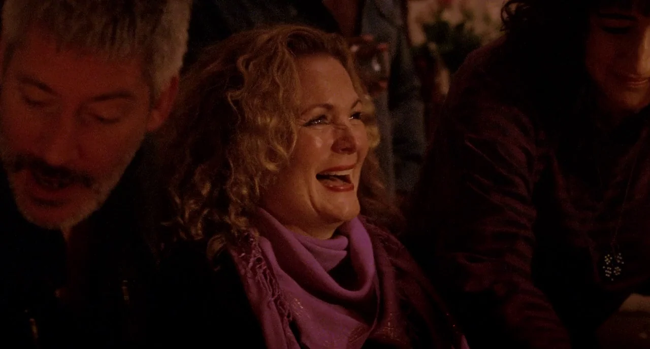 We Are The Best! (2013) movie still: medium — A dimly lit room with multiple people gathered around a table at night. A middle-aged blonde woman in…