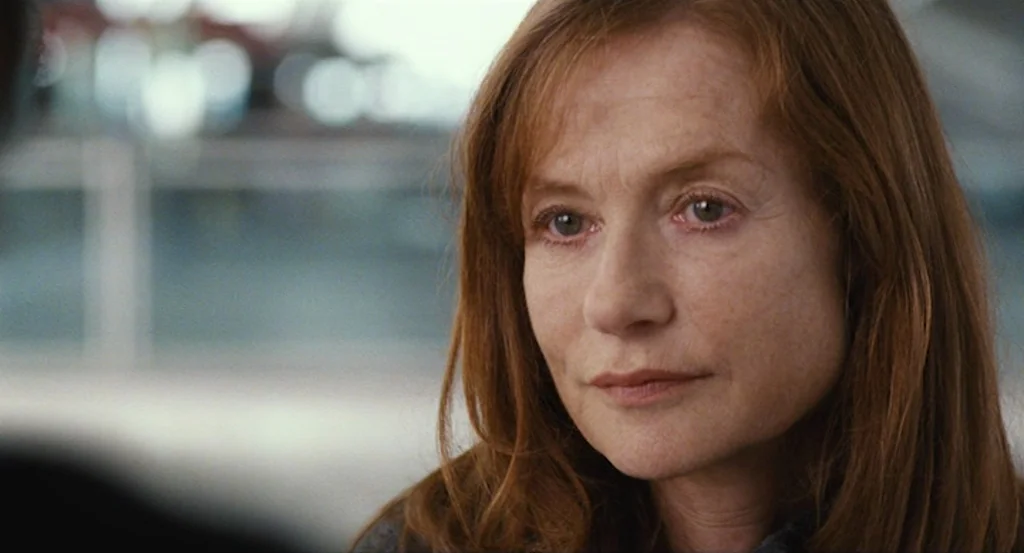 Louder Than Bombs (2015) movie still: closeup — A bright, modern interior space with blurry architectural lines visible in the background. A woman…