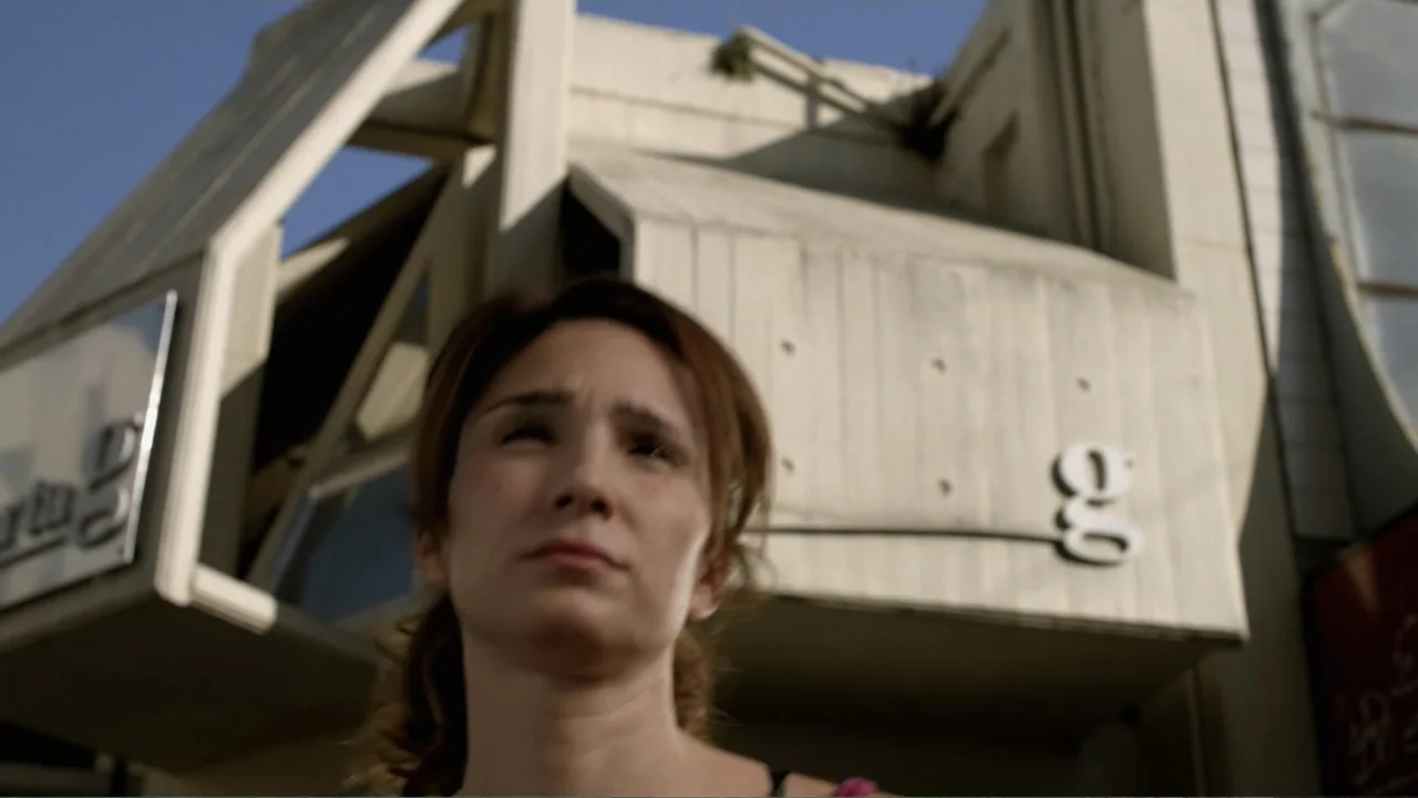 A Boyfriend for My Wife (2008) movie still: medium — A modern concrete building with angular geometric features stands against a clear blue sky. A…