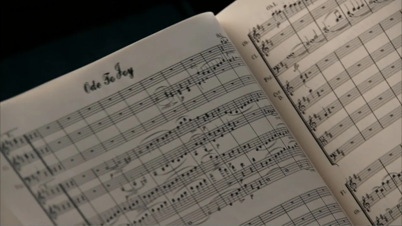 Get Smart (2008) movie still: closeup — A close-up view of an open orchestral score resting on a music stand. The paper shows printed musical…