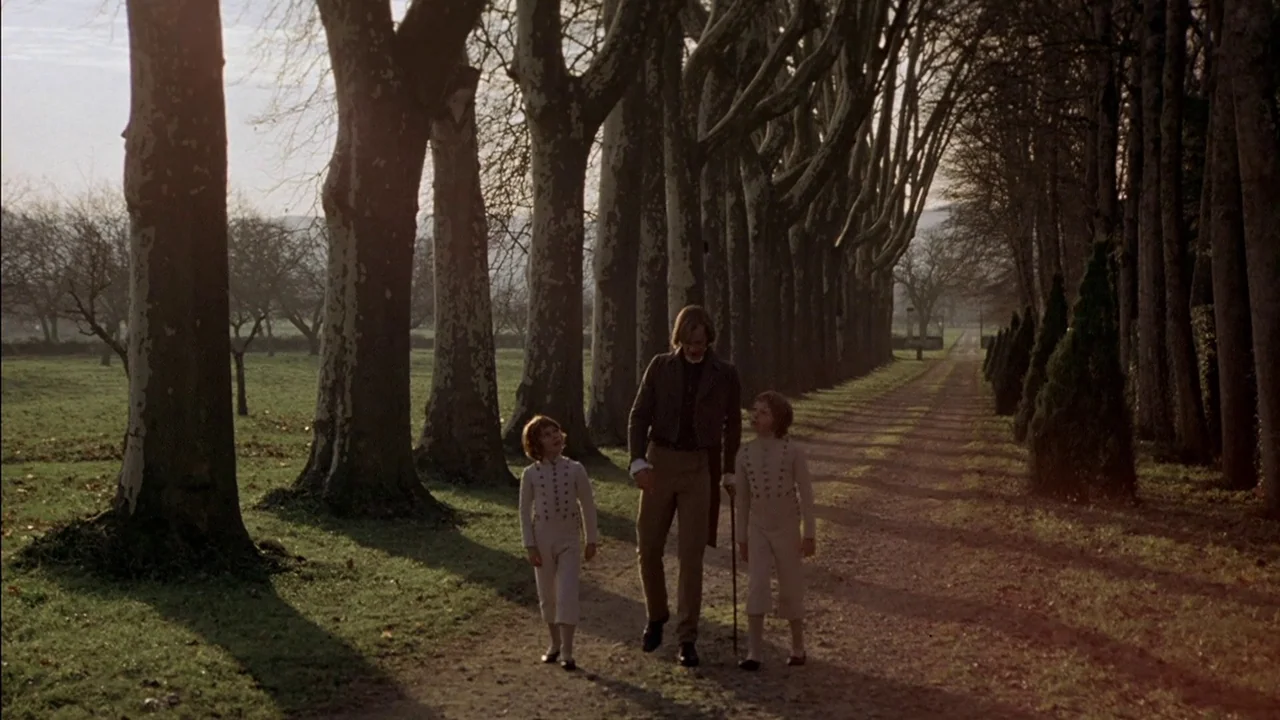 The Duellists (1977) movie still: fullbody — A long dirt path flanked by tall plane trees leads toward an open horizon. A man walks with two young…
