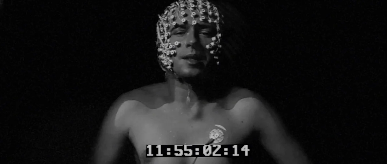 Vanishing Waves (2012) movie still: medium — A dark, void-like space contains a man rigged with scientific monitoring equipment. He wears an EEG…