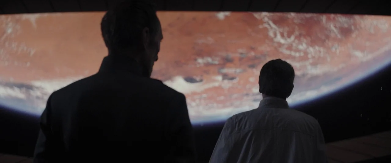Rogue One: A Star Wars Story (2016) movie still: medium — Two individuals stand in a dark, dimly lit cockpit or observation deck. They watch a large…