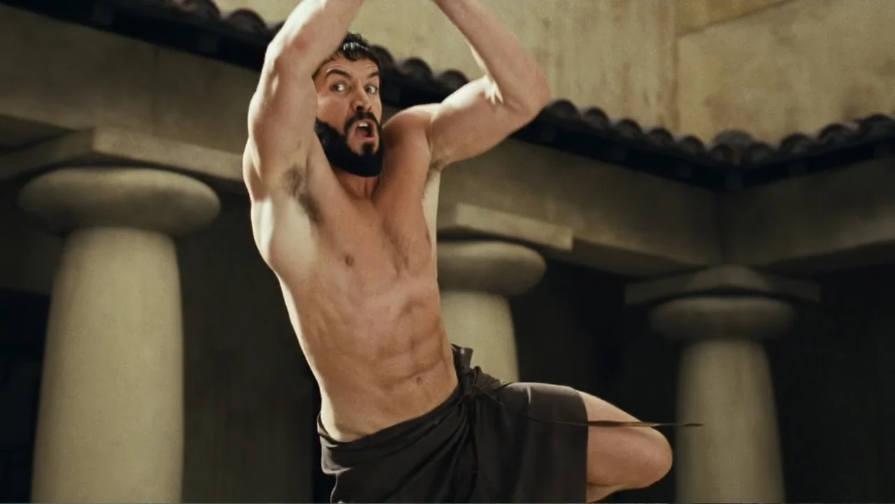 Meet the Spartans (2008) movie still: medium — An open courtyard features large stone pillars and tiled roofing under bright daylight. A muscular…