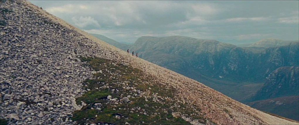 Your Highness (2011) movie still: wide — A vast, rugged mountain slope covered in loose scree and patches of grass. Three small figures traverse the…
