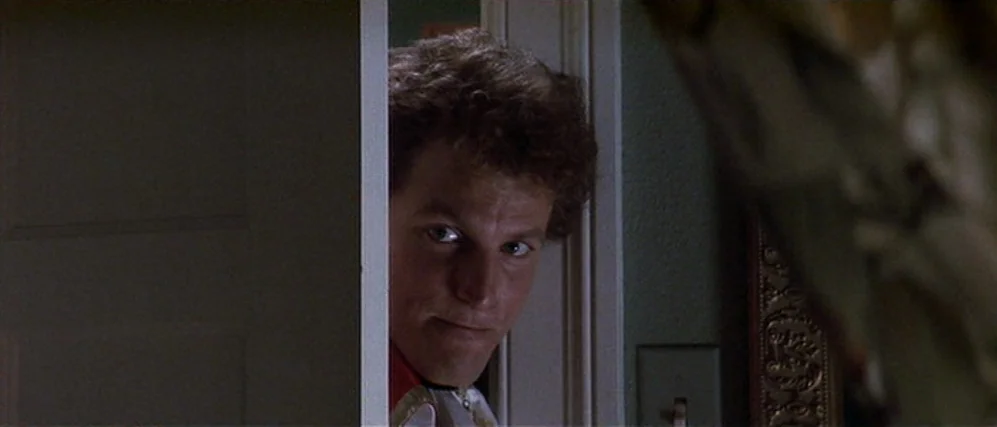 The People vs. Larry Flint (1996) movie still: closeup — A man looks through a partially opened door in a dark interior space. The door frame…