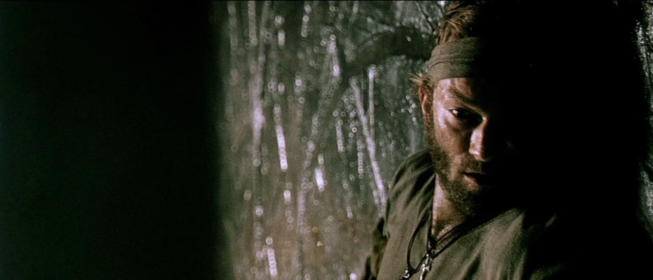 Renegade (2004) movie still: closeup — A man gazes out through a rain-streaked window pane into the darkness. Water droplets distort the light,…