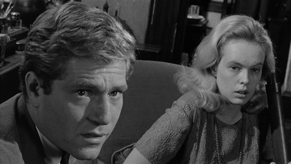 Who’s Afraid Of Virginia Woolf? (1966) movie still: medium — A domestic space features a man and woman seated closely together in a room. The man in…