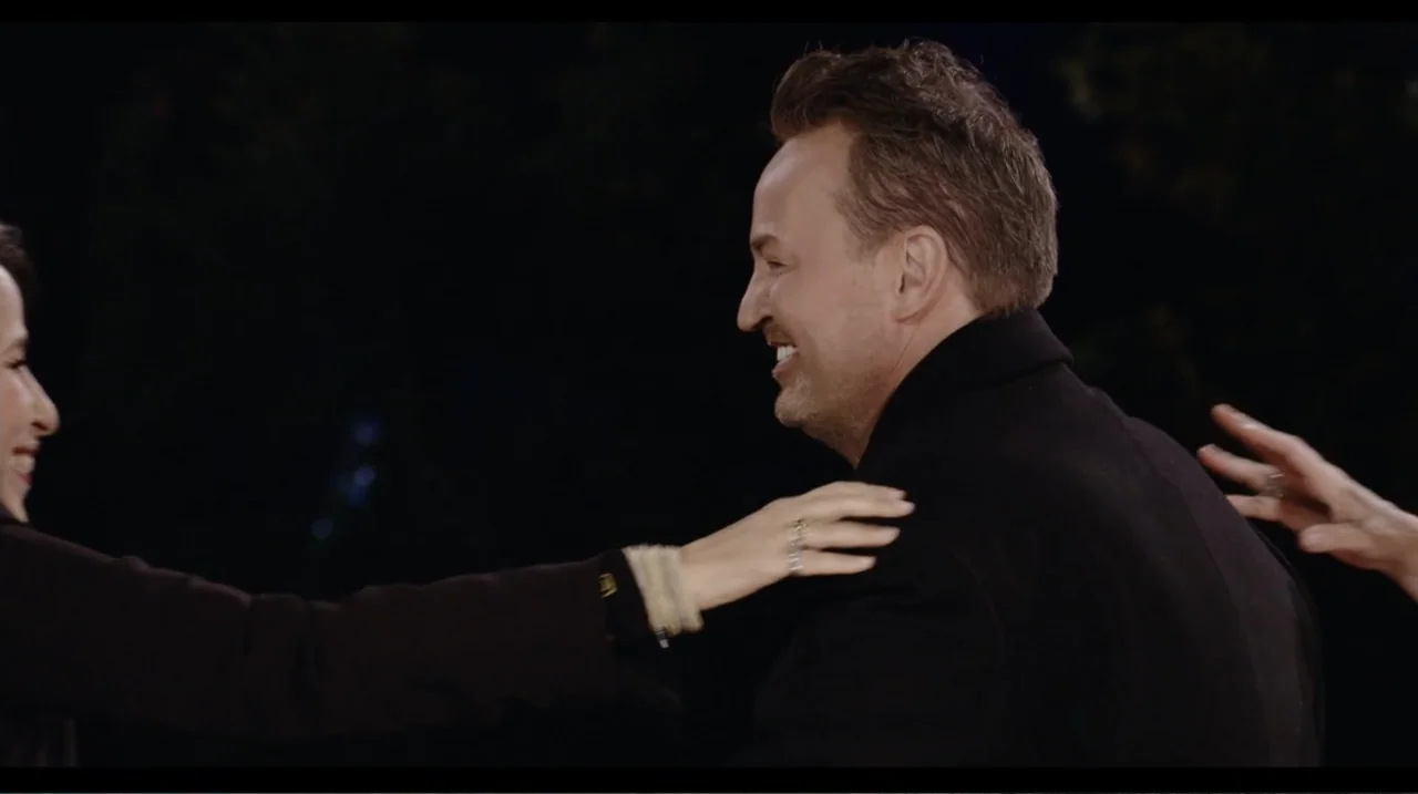 Friends: The Reunion (2021) movie still: medium — A dark, underexposed setting frames two individuals standing close to each other. A woman gestures…
