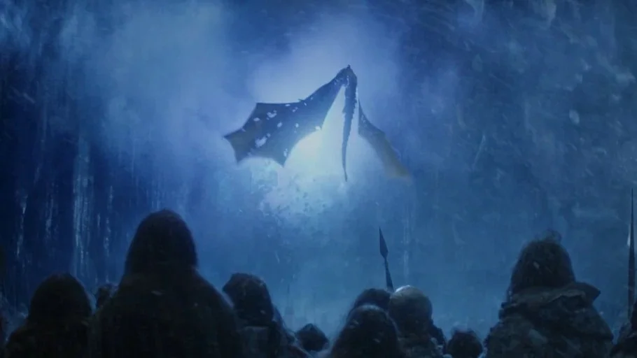 Game of Thrones (2017) movie still: wide — A massive dragon flies through a night sky filled with heavy falling snow and mist. A large crowd of…