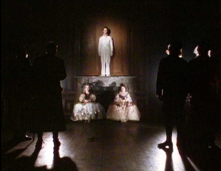 The Tempest (1979) movie still: wide — A dark parlor with a mantle piece serving as a raised platform. Three people in white formal clothing are…