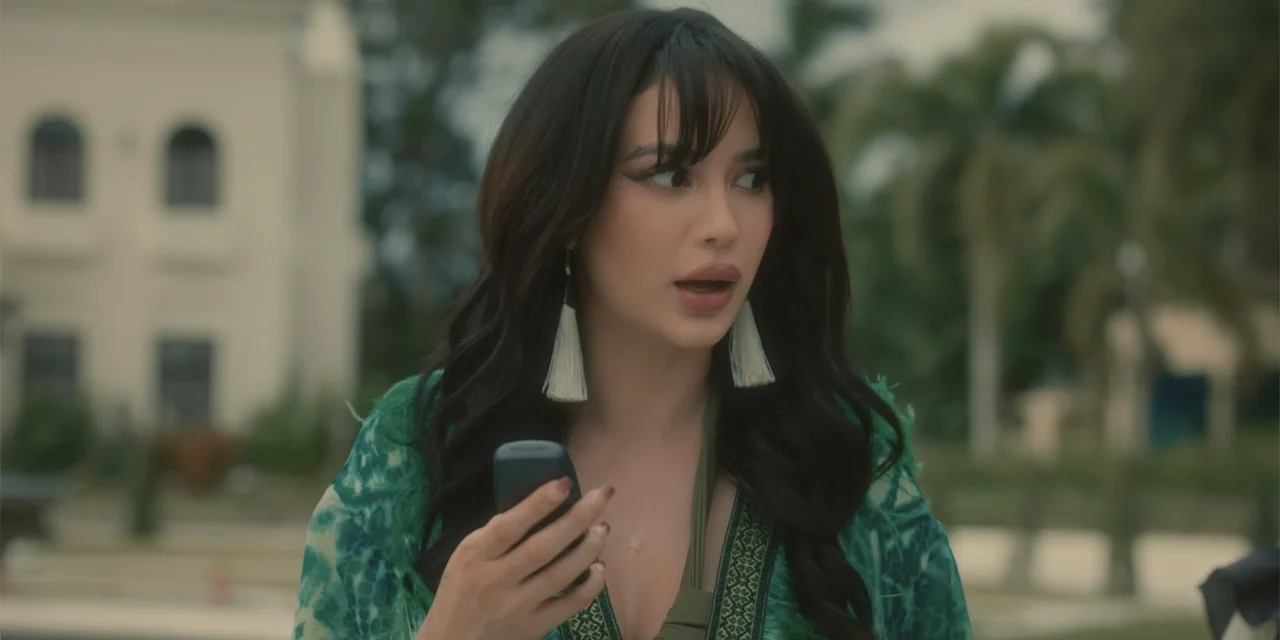 Ten Little Mistresses (2023) movie still: medium — A sunny outdoor resort area with blurred tropical foliage and a white arched building facade. A…