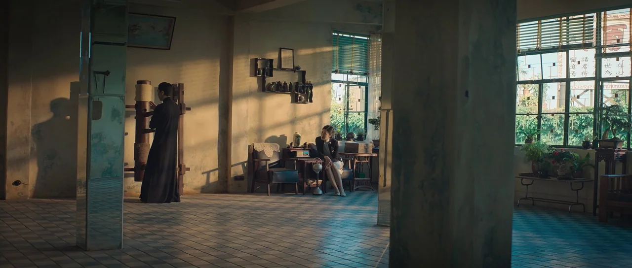 Ip Man 3 (2015) movie still: wide — A spacious room features a tiled floor, large windows, and vintage wooden wall decorations. A man strikes a…