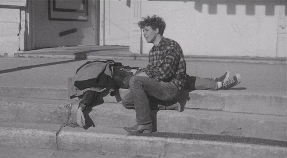 The Last Picture Show (1971) movie still: fullbody — Concrete steps leading to a nondescript building entrance with an overhanging ledge. A young…