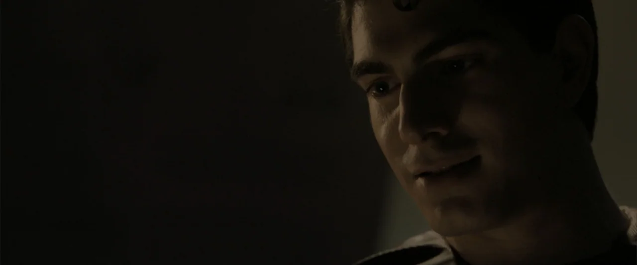 Superman Returns (2006) movie still: closeup — A dark indoor space contains a man partially lit by directional light. The subject looks down with a…