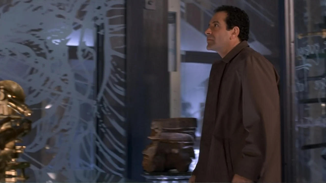 13 Ghosts (1960) movie still: medium — A modern museum exhibit space features etched glass partitions and displayed artifacts. A man in a brown coat…