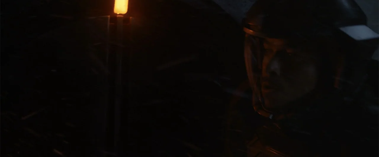 DISTANT (2026) movie still: closeup — A dark outdoor space during a night blizzard with falling snow visible in motion. A man wearing a tactical…