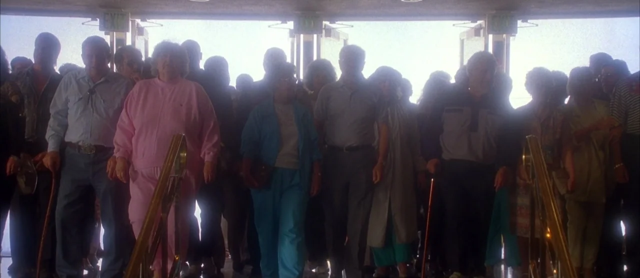 Casino (1995) movie still: wide — A crowd of people descends a set of stairs toward a bright exterior entrance. The subjects are backlit by…