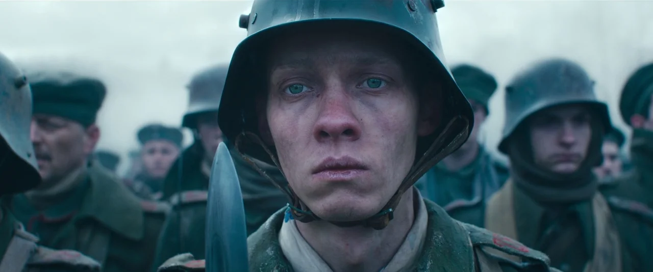 All Quiet on the Western Front (2022) movie still: closeup — A group of soldiers in muddy military gear march through a thick, foggy battlefield…