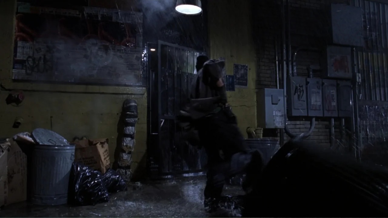 Miss Congeniality (2000) movie still: medium — An urban alleyway features yellow-painted brick walls with industrial metal fixtures and garbage…