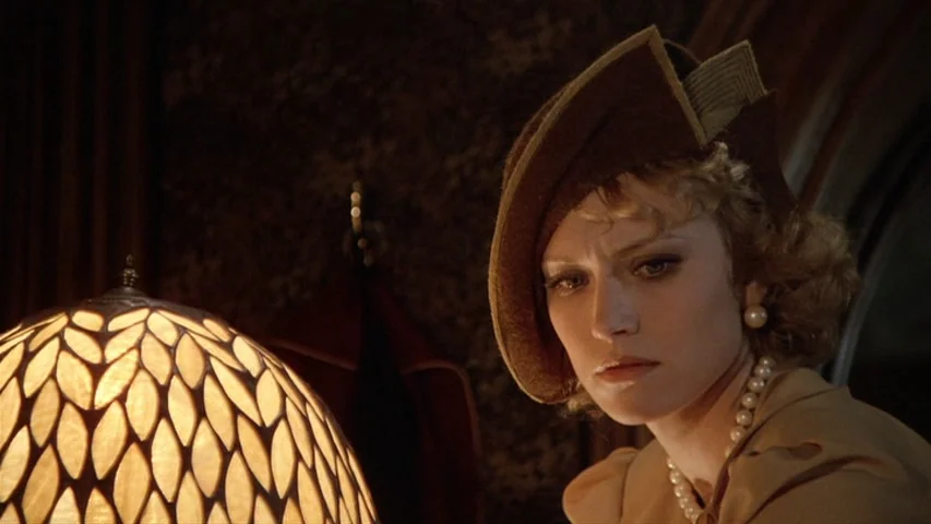 Once Upon A Time In America (1984) movie still: closeup — A dimly lit room features a glowing patterned lamp beside a woman in period clothing. The…