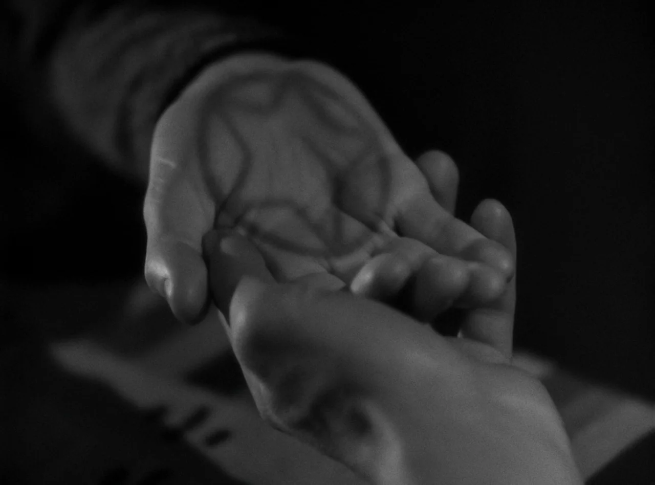 The Wolf Man (1941) movie still: A haunting, extreme closeup of two hands meeting in the darkness to reveal a cryptic star symbol etched into a…