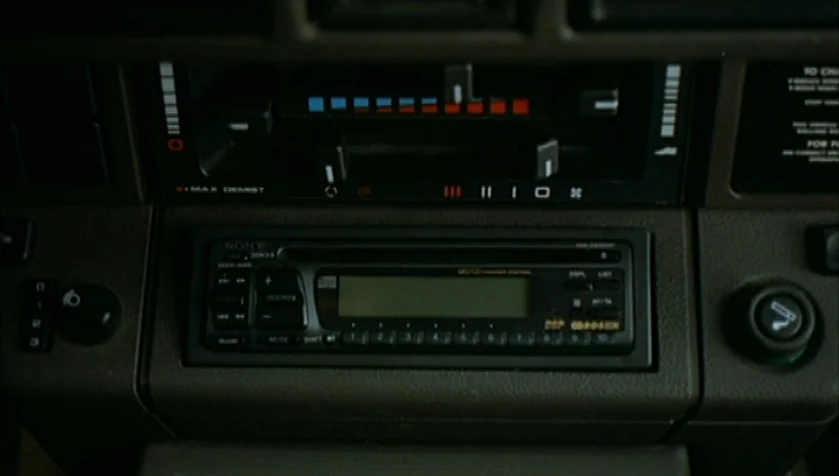 Funny Games (1997) movie still: closeup — A close-up view shows a 1990s car dashboard with a Sony radio unit. The console features climate control…