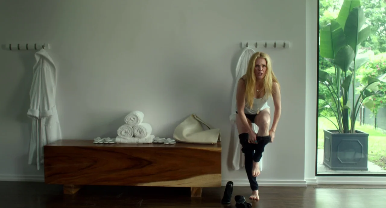 Maps to the Stars (2014) movie still: fullbody — A modern, minimalist space features a wooden bench, stacked towels, and a large plant. A blonde…